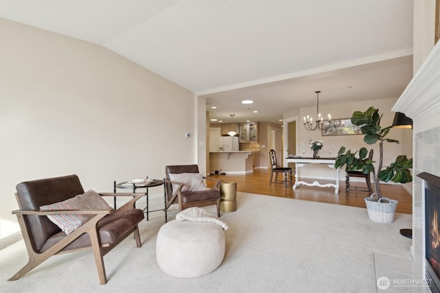 sitting room with vaulted ceiling, a lit fireplace, recessed lighting, and a notable chandelier