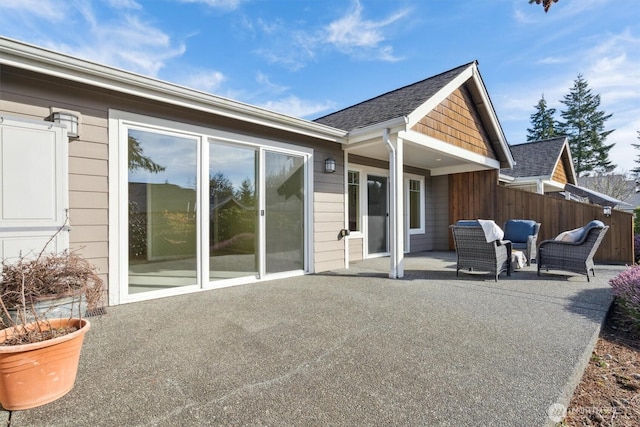 back of house with a shingled roof, a patio area, and fence