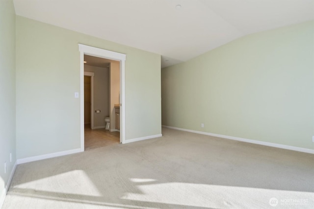 unfurnished bedroom with carpet floors, baseboards, ensuite bathroom, and lofted ceiling