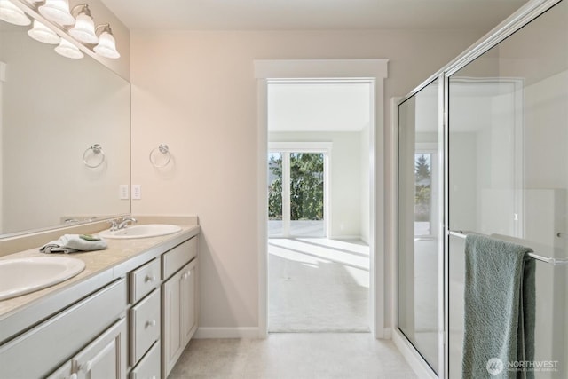 full bathroom featuring double vanity, a shower stall, and a sink