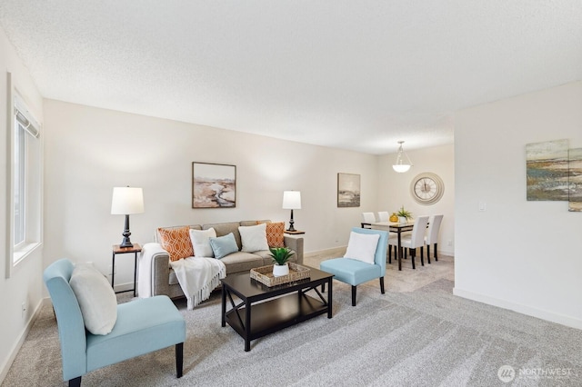 living area with baseboards, a textured ceiling, and light colored carpet