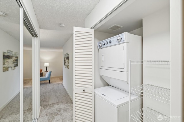 laundry room with a textured ceiling, light carpet, laundry area, visible vents, and stacked washing maching and dryer