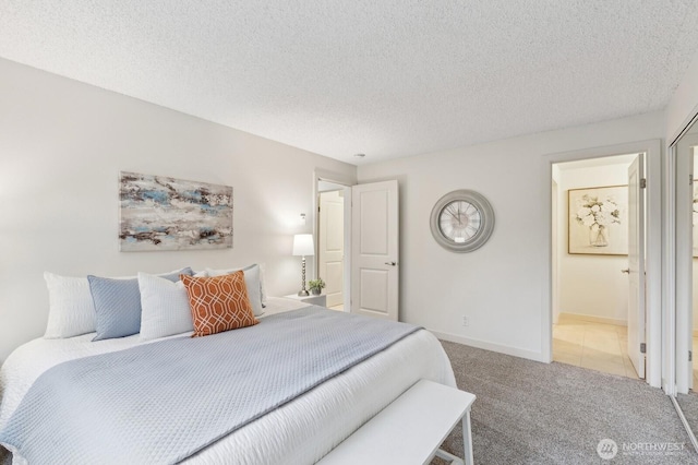 carpeted bedroom featuring connected bathroom, baseboards, and a textured ceiling