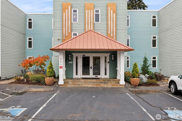 exterior space featuring french doors, uncovered parking, a porch, a standing seam roof, and metal roof