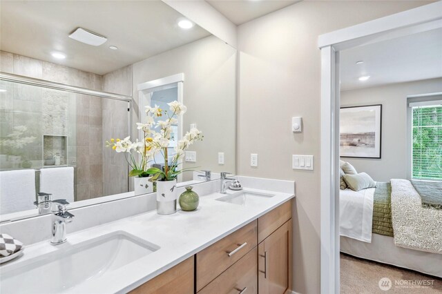 ensuite bathroom featuring a stall shower, double vanity, a sink, and ensuite bathroom