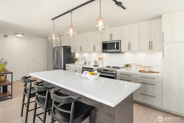 kitchen featuring light wood-style floors, appliances with stainless steel finishes, backsplash, and a breakfast bar area