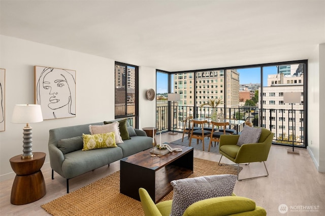 living area featuring a city view, baseboards, a wall of windows, and wood finished floors