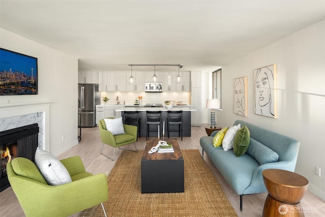 living area featuring light wood finished floors, a premium fireplace, rail lighting, and baseboards