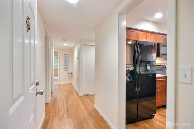 hallway featuring baseboards and light wood finished floors