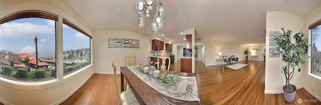 interior space featuring vaulted ceiling, wood finished floors, and baseboards