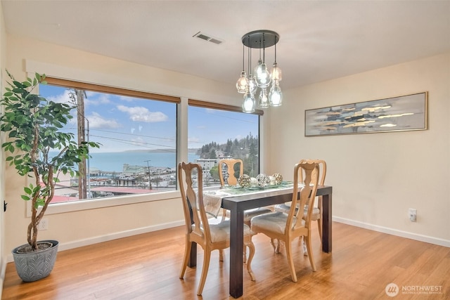 dining area with wood finished floors, visible vents, and baseboards