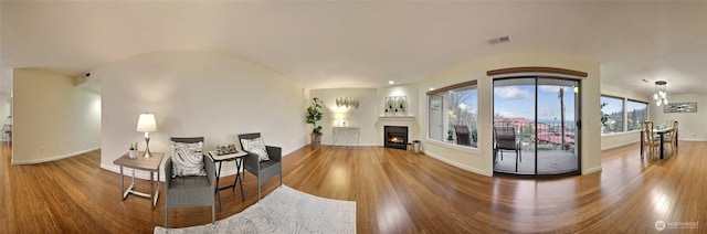 living area featuring lofted ceiling, wood finished floors, and visible vents