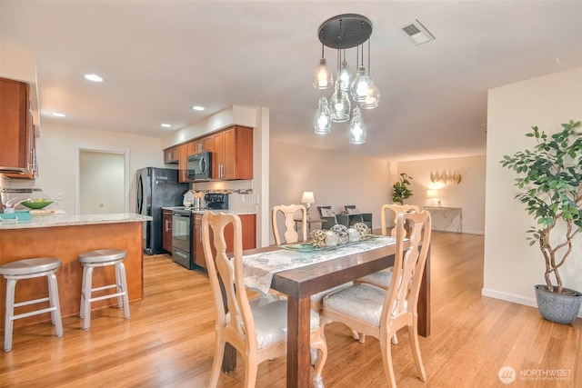 dining space with baseboards, light wood-type flooring, visible vents, and recessed lighting