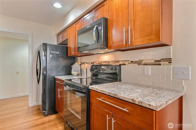 kitchen featuring black appliances, light wood finished floors, and brown cabinets