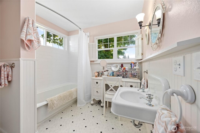 bathroom with wainscoting, shower / bathtub combination with curtain, and tile patterned floors