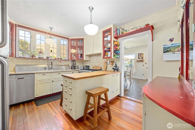 kitchen featuring wood-type flooring, a sink, wooden counters, and stainless steel dishwasher