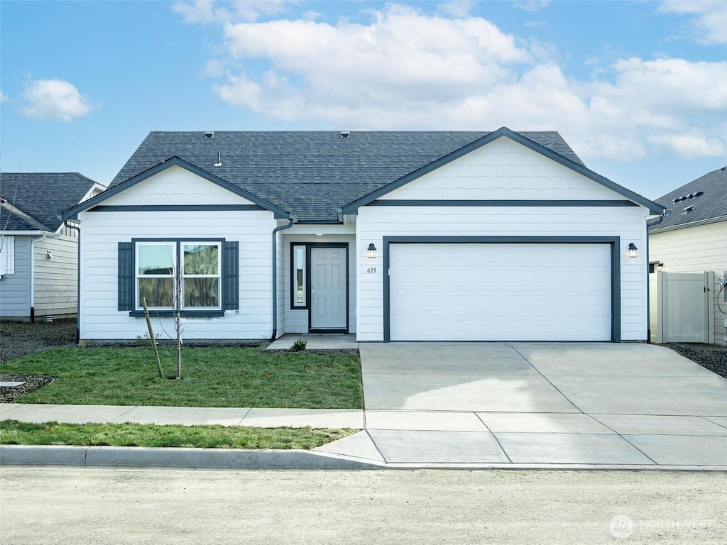 ranch-style house featuring a garage, fence, concrete driveway, roof with shingles, and a front yard