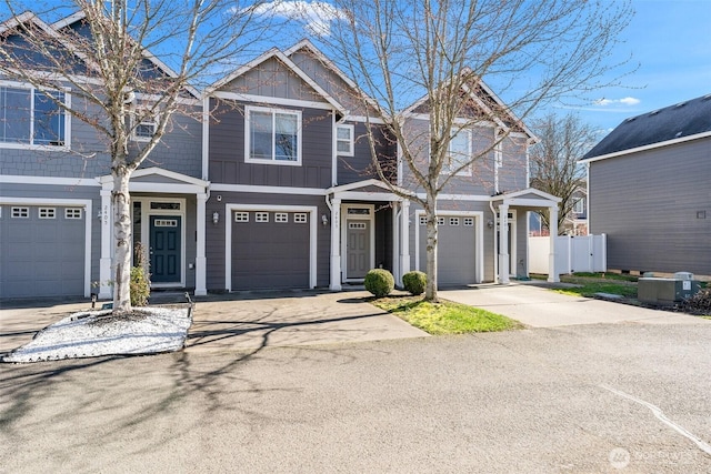 view of front of property with a garage, driveway, board and batten siding, and fence