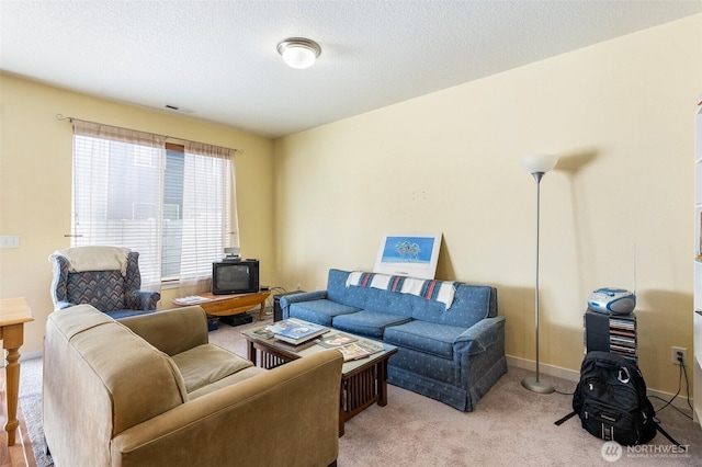 living room featuring light carpet, baseboards, visible vents, and a textured ceiling