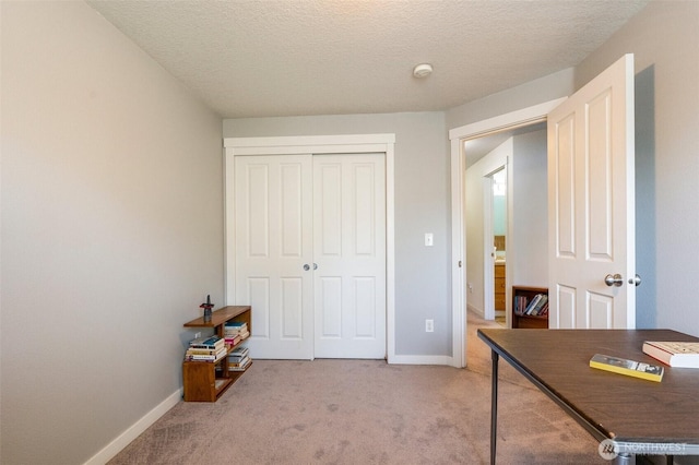 home office featuring light carpet, a textured ceiling, and baseboards