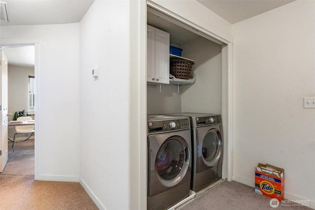 clothes washing area featuring light carpet, cabinet space, baseboards, and washing machine and clothes dryer