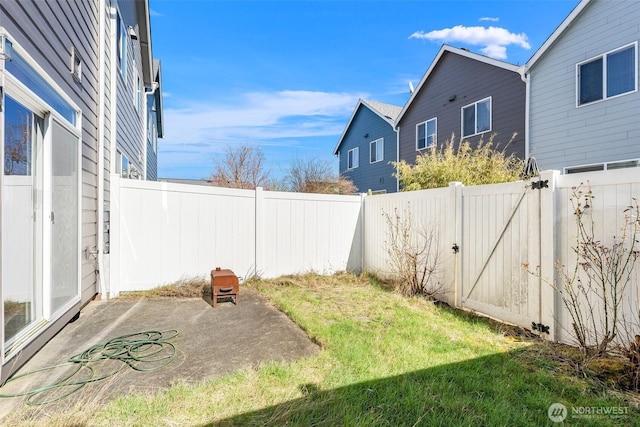 view of yard with a patio, a fenced backyard, and a gate