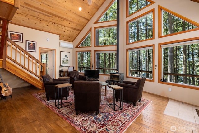 living room featuring a wood stove, a wall unit AC, wooden ceiling, stairs, and hardwood / wood-style flooring