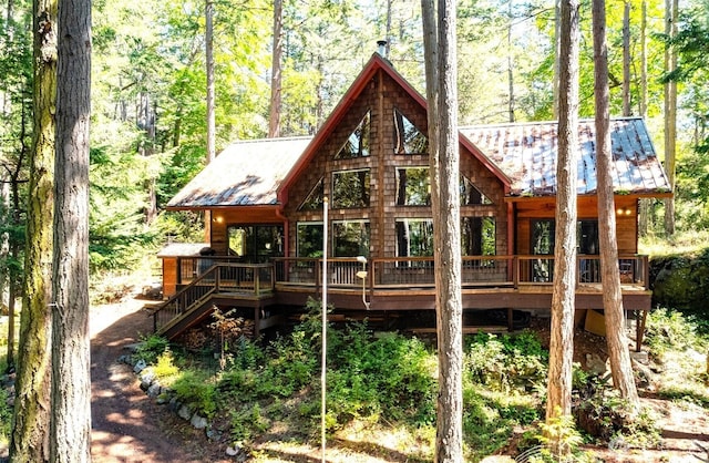 rear view of house featuring metal roof, a deck, a forest view, and stairs