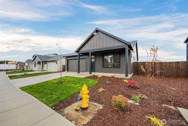 view of front facade featuring concrete driveway, an attached garage, board and batten siding, fence, and a front lawn