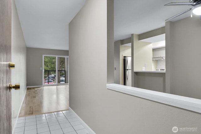 corridor with baseboards and tile patterned floors