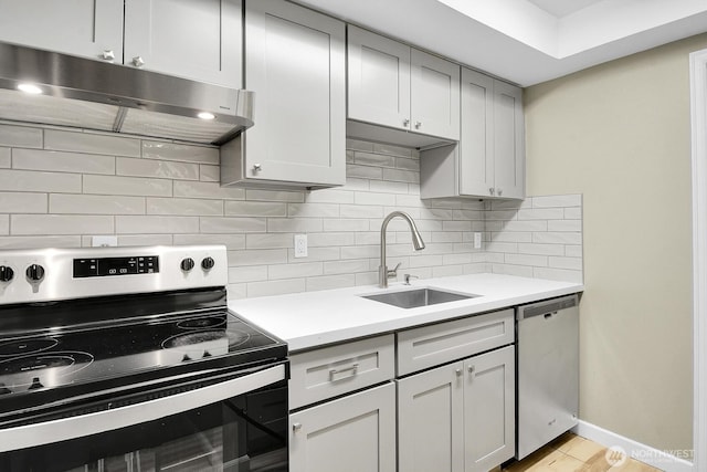 kitchen with stainless steel appliances, a sink, light countertops, and under cabinet range hood