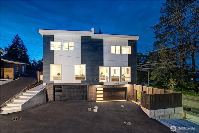 contemporary home with a garage, driveway, and brick siding