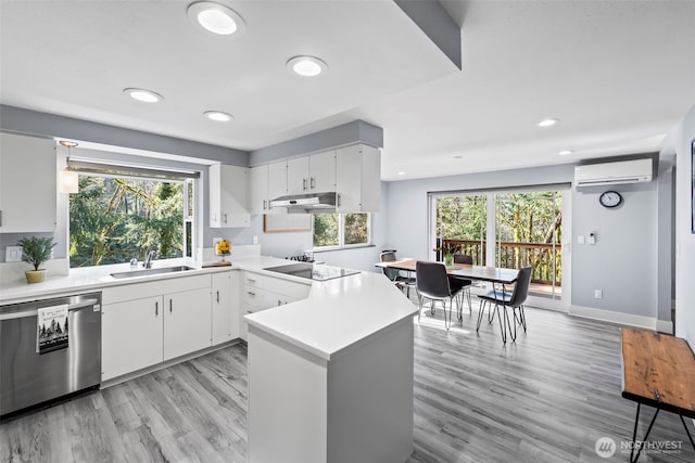 kitchen featuring under cabinet range hood, a sink, light countertops, dishwasher, and a wall mounted air conditioner