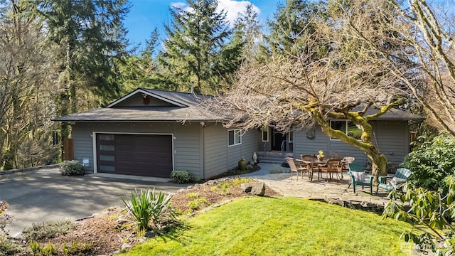 view of front facade with a yard, a shingled roof, aphalt driveway, and a garage