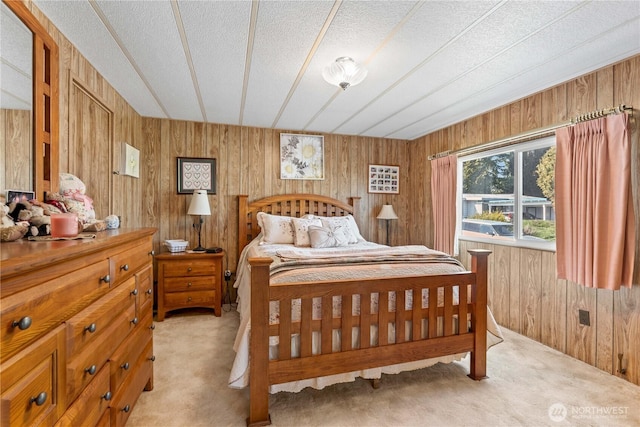 bedroom with wooden walls, a textured ceiling, and light colored carpet