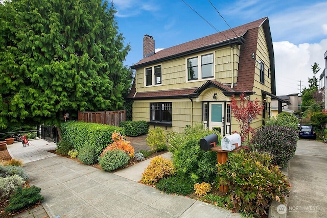 view of front of home featuring roof with shingles, a chimney, fence, and a gambrel roof