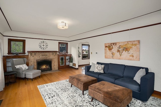 living area featuring a fireplace with flush hearth, visible vents, arched walkways, and wood finished floors