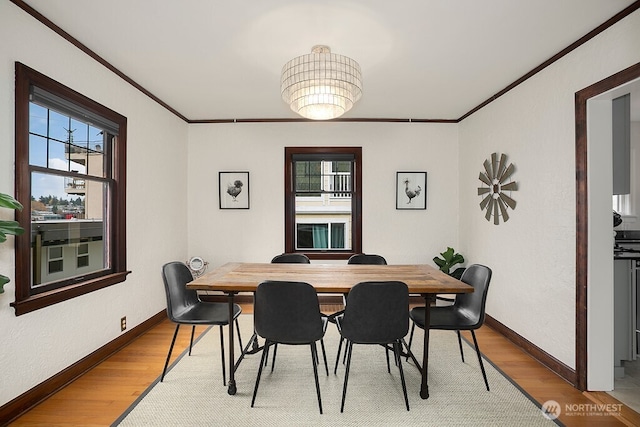 dining area with baseboards, wood finished floors, and crown molding