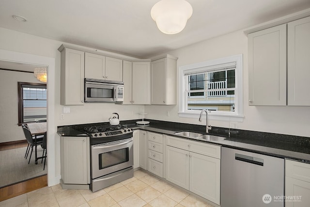 kitchen featuring appliances with stainless steel finishes, a sink, baseboards, and light tile patterned floors