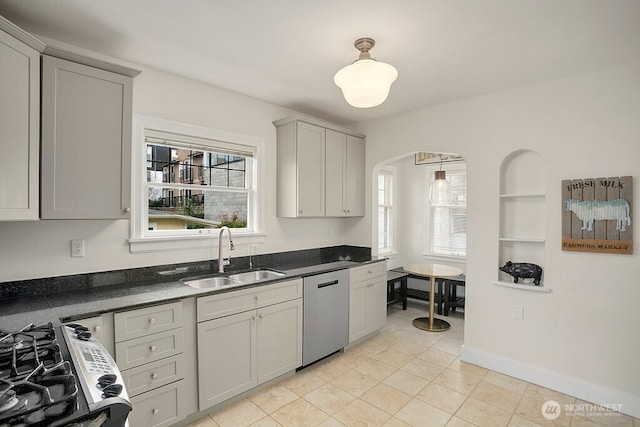 kitchen featuring dark countertops, a healthy amount of sunlight, a sink, and stainless steel dishwasher