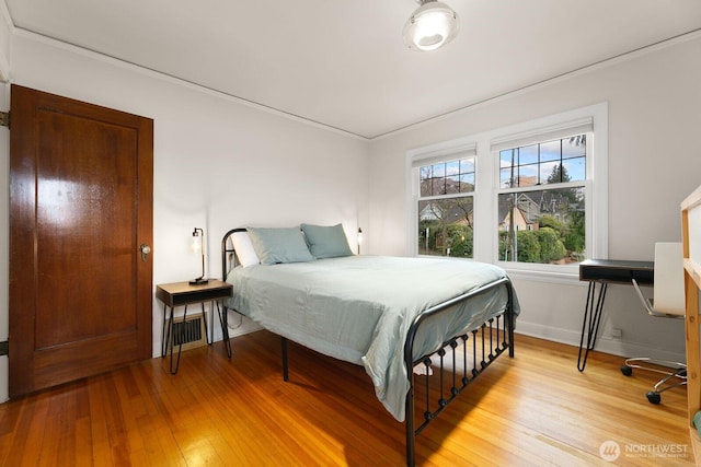 bedroom featuring ornamental molding, light wood-style flooring, and baseboards