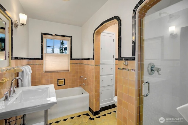 full bath with tile walls, toilet, a stall shower, a sink, and tile patterned flooring