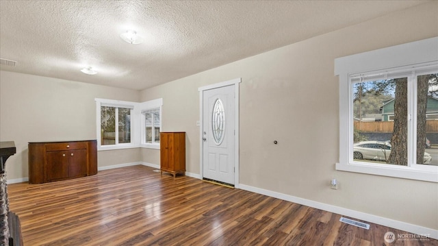 entryway with baseboards, visible vents, and wood finished floors