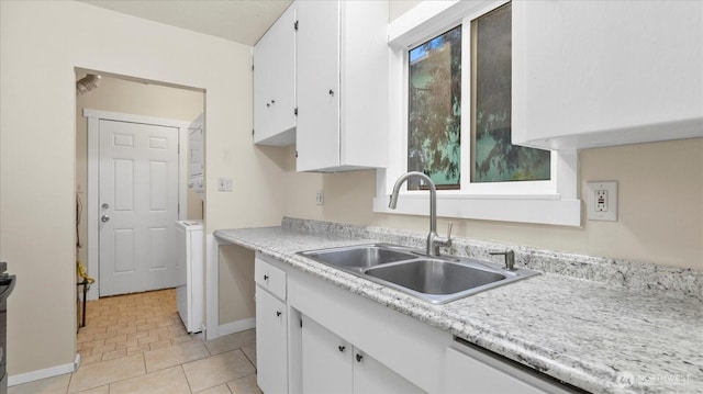 kitchen featuring light tile patterned floors, light countertops, white cabinetry, a sink, and washer / dryer