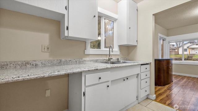 kitchen with white cabinets, a sink, and light wood finished floors