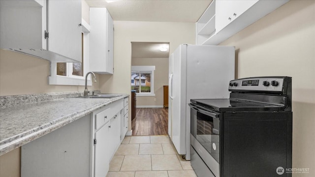 kitchen featuring light tile patterned floors, white cabinets, light countertops, stainless steel range with electric stovetop, and a sink