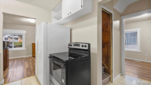 kitchen featuring black microwave, baseboards, electric stove, and light tile patterned flooring