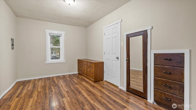 unfurnished bedroom featuring baseboards, dark wood finished floors, and a textured ceiling