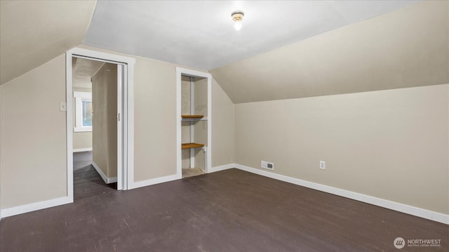 additional living space featuring lofted ceiling, visible vents, baseboards, and wood finished floors