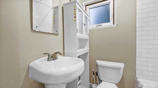 bathroom featuring toilet, walk in shower, and a sink